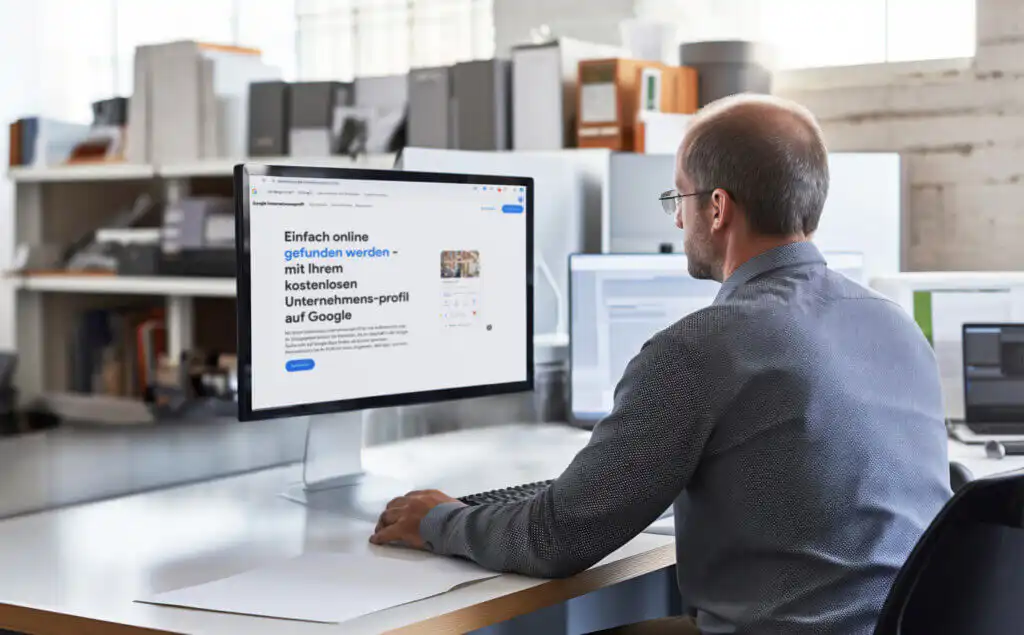 Man sitzt in einem Büro vor einem Bildschirm und hat die Webseite vom Google Unternehmens Profil geöffnet.